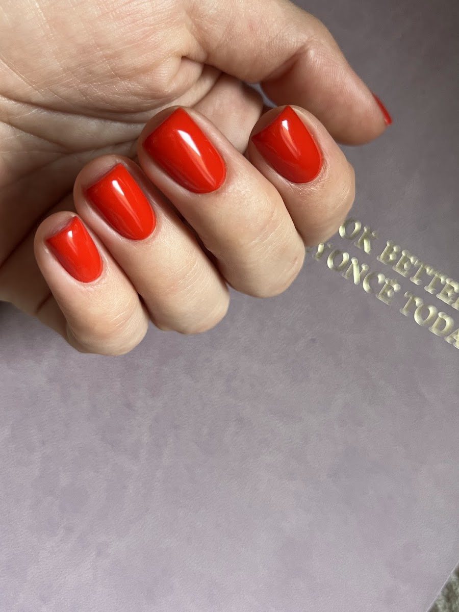 Manicura rojo intenso sobre una libreta de tapas grises